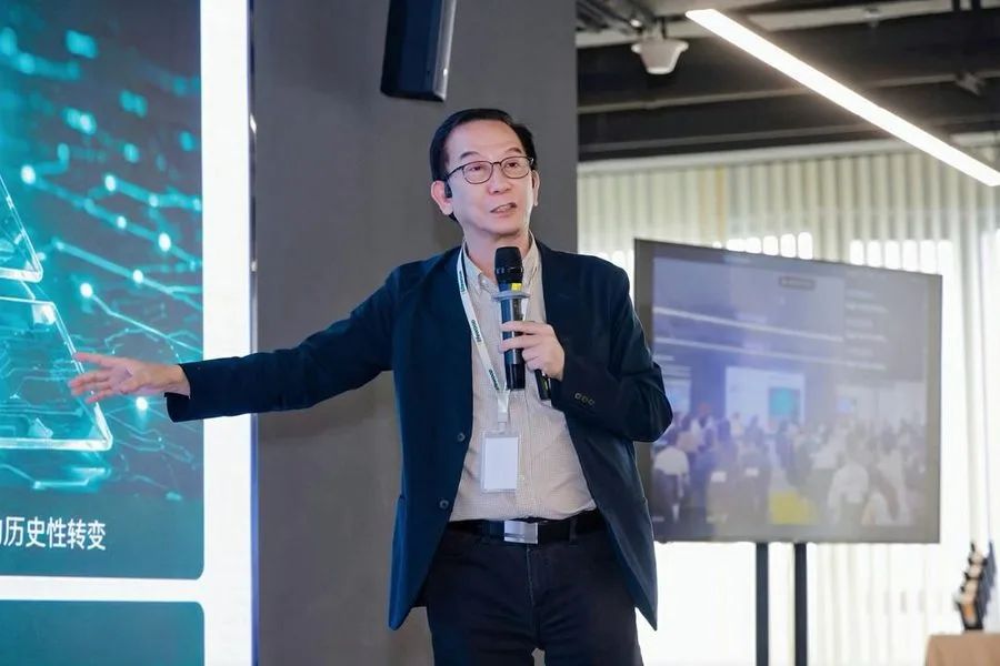 Lifewood Founder and CEO Ronald Cheung speaking with a handheld microphone on stage at Tech Talk 2026, beside a screen showing a Chinese-language slide.